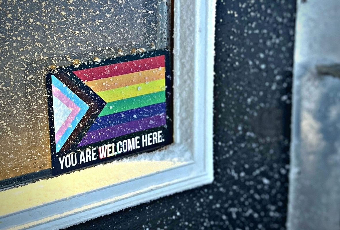 A You Are Welcome Here pride flag sticker in a window